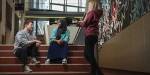 To studenter sitter i en trapp på OsloMet. En annen star ved siden av. De snakker og ler.