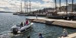 Seaside in the centre of Oslo, a small leisure boat on the fjord and people soaking in the sun on land.