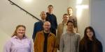Gruppebilde av nye forskere ved NIBR og administrerende direktør i 2023 i en hvit trappeoppgang som ser i kamera og smiler.