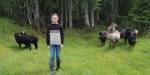 girl in knitted sweater in a field surrounded by sheep