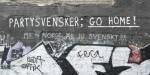 Graffiti på en murvegg i Oslo hvor det står: Partysvensker go home! Med teksten men Norge er jo svensk skrevet under.