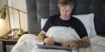 Man working on a laptop while in bed.