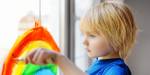 Et barn tegner en regnbue på et vindu.