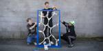 Three students painting a partition they made blue