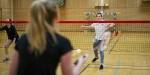 Unge studenter spiller badminton i gymsal