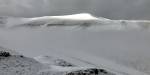 Svalbard-landskap med fjell og en dyp dal i mellom. Dekket av snø, deler av fjellene stikker opp av snøen.