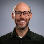 Portrettbilde av forsker Gavin McCrory ser i kamera og smiler.