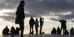 Silhouettes of people on the opera house rooftop in front of an evening sky.