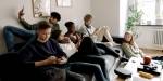 Six teenagers relaxing together, and using their mobile phones.