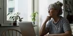 elderly woman with computer looking out of window