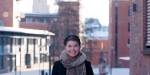 Bilde av en smilende masterstudent Marianne Christiansen, med Campus Pilestredet på OsloMet i bakgrunnen.