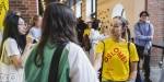 En smilende student med gul OsloMet-t-skjorte blant mange andre studenter.