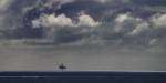A lonely oil platform in the sea, with a cloudy sky.