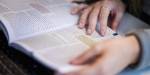 Close up picture of hands holding an open book.