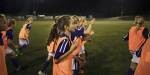 Girls playing football outside at night.
