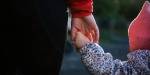 Close-up of an early childhood education teacher holding a little child by the hand.