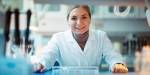 Frida Sitter i lab-frakk på en lab og smiler inn i kameraet