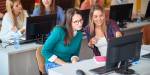 To unge studenter ser oppmerksomt inn i en dataskjerm. Flere studenter og dataskjermer i bakgrunnen.