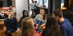 A group of students laughing and playing a board game in a café. Photo: Benjamin A. Ward