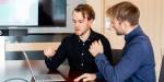 Kristian og Kristoffer diskuterer foran datamaskinen. De sitter nær hverandre, og gestikulerer med armene.