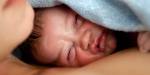 Ansikt av et nyfødt barn delvis dekket av dyne