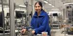 Maryam prepares the machinery in the laboratory. We see laboratory equipment in the background.