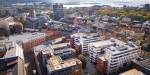 Drone view of Campus Pilestredet with its brick and glass buildings in the middle of the city centre. The Oslo Fjord is in the backgrouns.