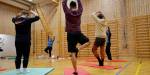 studenter og lærer gjør yoga i gymsalen
