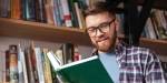 Young man reading book in library.