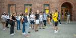 En gruppe nye studenter står foran en teglstelgnsbygning i Pilestredet på OsloMet. Foran dem står to faddere i gule t-skjorter.