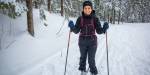 Woman smiling and skiing in a snowy forest.