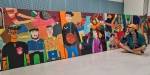 Ahmed Umar foran fellesprosjektet til elevene på Hersleb - et stort fargerikt maleri på 6 x 1,2 meter. På maleriet ser vi selvportrett av elevene i ulike sosiale sammenhenger.