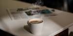 Illustrasjonsfoto av en kaffekopp med rykende varm kaffe og en avis