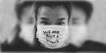 jente med munnbind hvor det står skrevet på "we are not a virus"