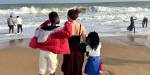 On a beach in Togo. Two adult women and a child are holding around each other and looking out at the ocean