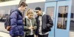 tre ungdommar ser på telefon saman