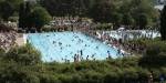 Lawn and pool at Nebbursvollen water park. There are many people in the pool, as well as on the lawn.