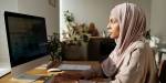 Kvinne i hijab setter ved datamaskin