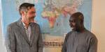 Kristian Tronstad and Sadiq Boateng standing in front of a colorful world map with national flags displayed below.