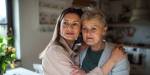 Adult daughter giving comfort to older mother in kitchen