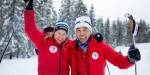 Woman and man holding around each other and raising their ski poles in the air.