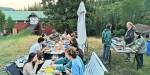 The students sit gathered around three tables out in the yard eating shrimp