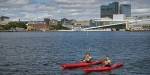 Two kayakers on the Oslo Fjord with  Oslo's urban downtown in the background.