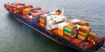 et lasteskip på havet fullastet med containere i flere forskjellige farger som frakter varer over lange avstander