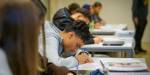 Ung gutt sitter og skriver i klasserom