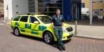 Øyvind Bauge lener seg mot en engelsk ambulansebil iført fult paramedicantrekk. Han smiler fornøyd.