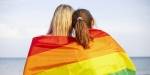 To unge jenter med ryggen til tullet inn i regnbogeflagg