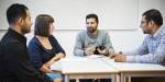 Four students discussing around a table.