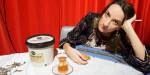 Bilde fra Aje Victoria Bigsets masteroppgave. Aje sitter ved et bord med en kopp te, en boks med sodd og en vaffel.