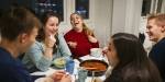 Five students having dinner, laughing and having fun together.